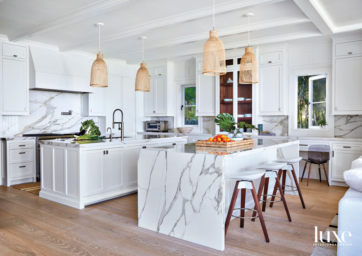 white kitchen with marble countertops, bamboo pendants, wood flooring and white stools