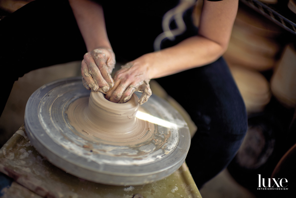 Hands shaping clay on a pottery wheel