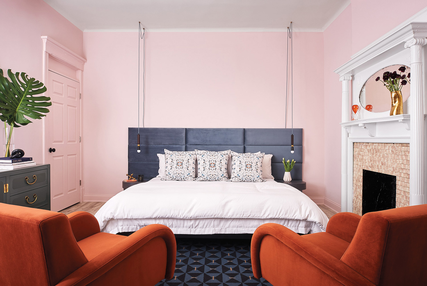 Hotel bedroom with pink walls, vibrant furnishings and a fireplace