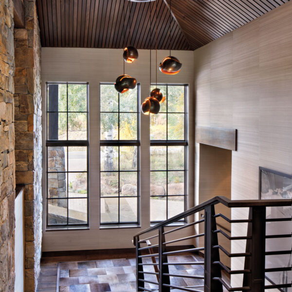 Joy Fills A Swiss Chalet-Inspired Colorado Home With Global Notes mountain-style stairway features an elegant light fixture