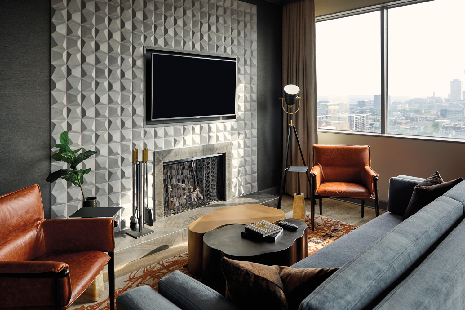 A sunlit living room with multi-dimension fireplace wall, upholstered furniture and working fireplace