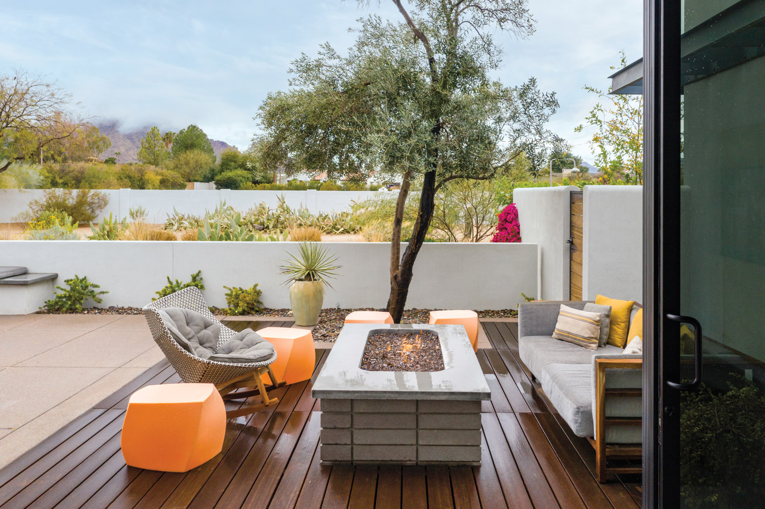 Outdoor living space with deck, fire pit, orange accents and walled garden.