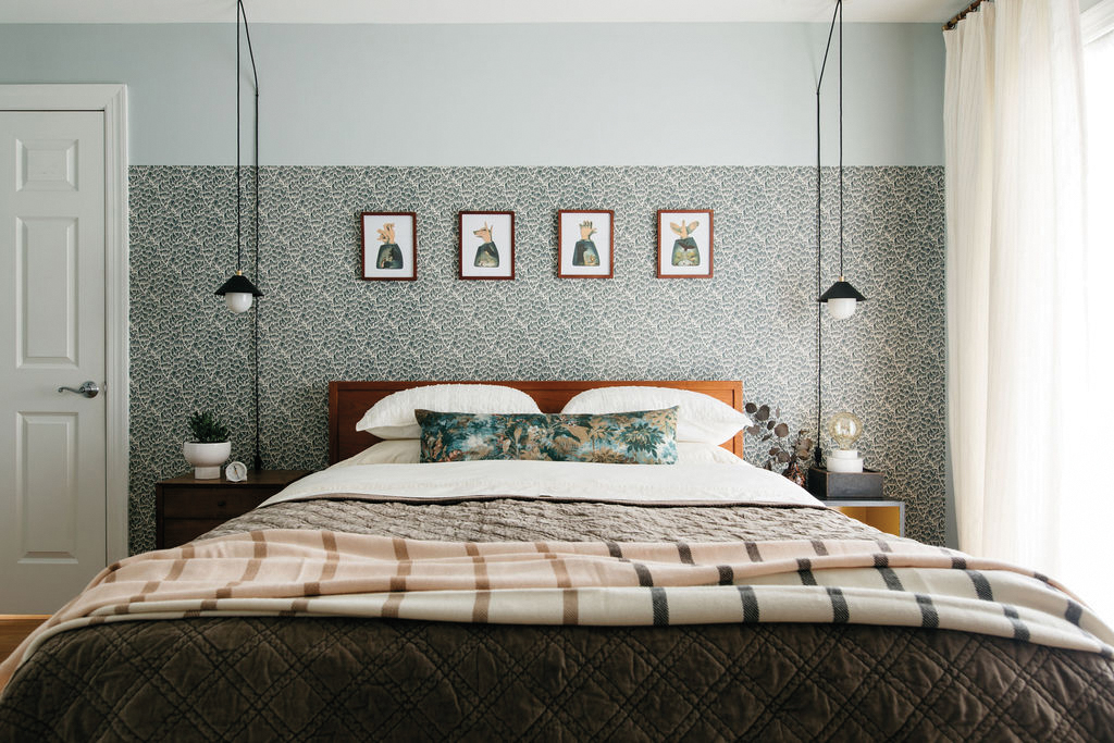 Bedroom with a black-and-white-patterned wallcovering, pendant lighting and neutral stripped bedding.