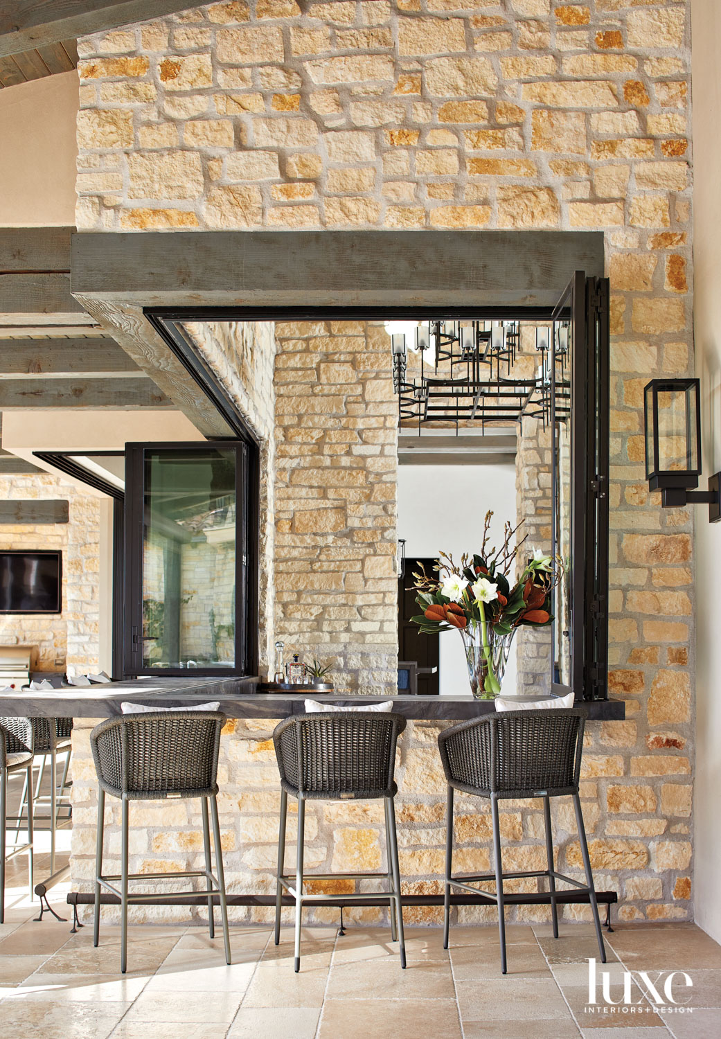 A patio bar with three black stools lined up along it.