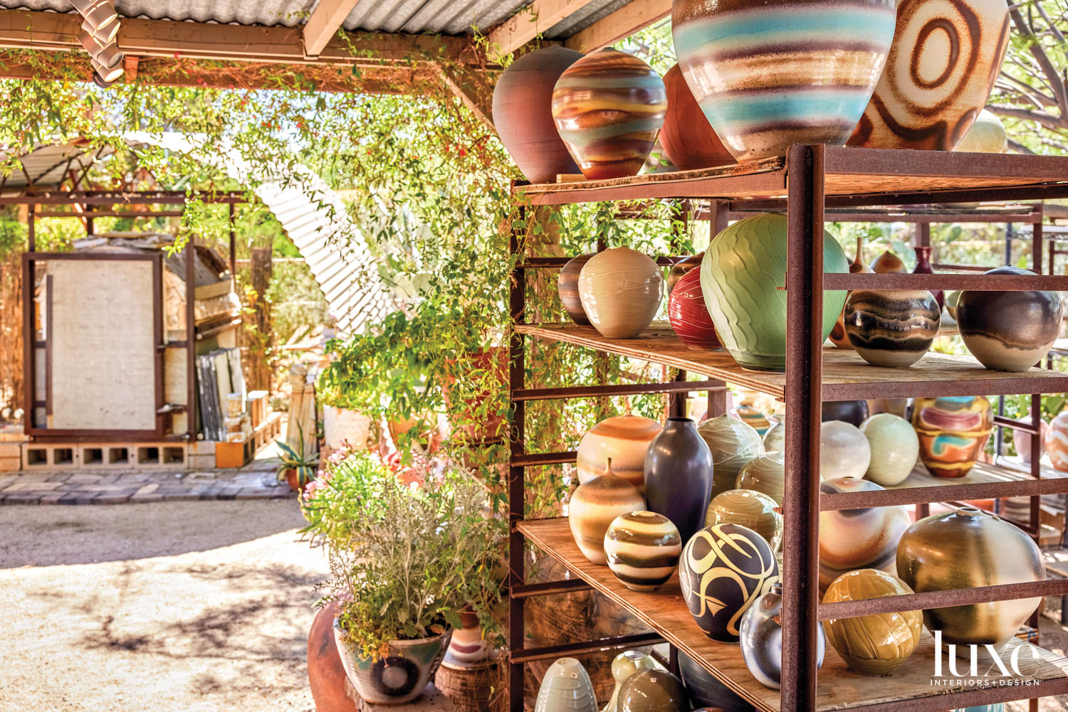 An outdoor ceramics studio with shelves holding pots.