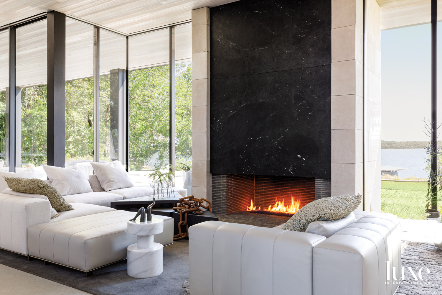 A living room with a floor-to-ceiling fireplace surrounded by white seating.