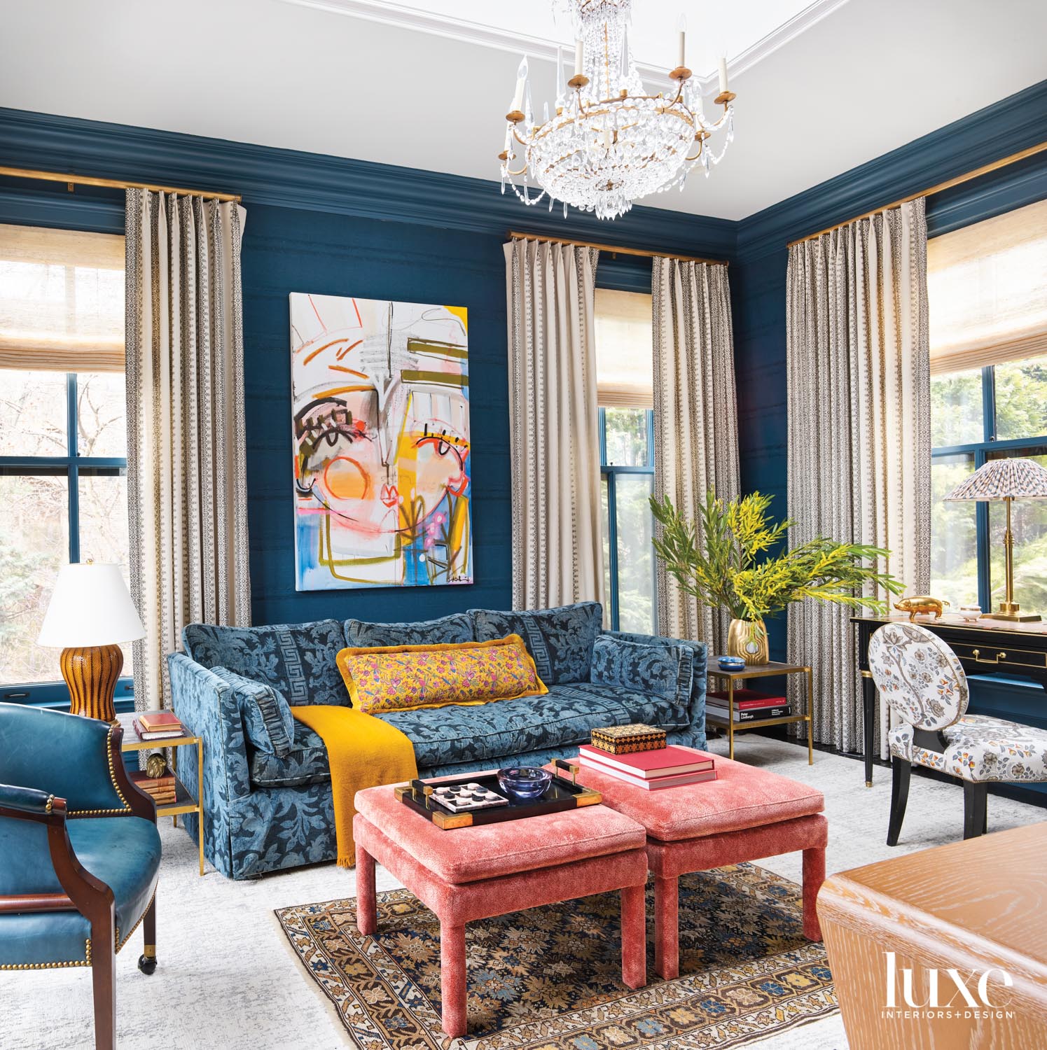 A study with a blue patterned couch and two pink ottomans by Summer Thornton Design