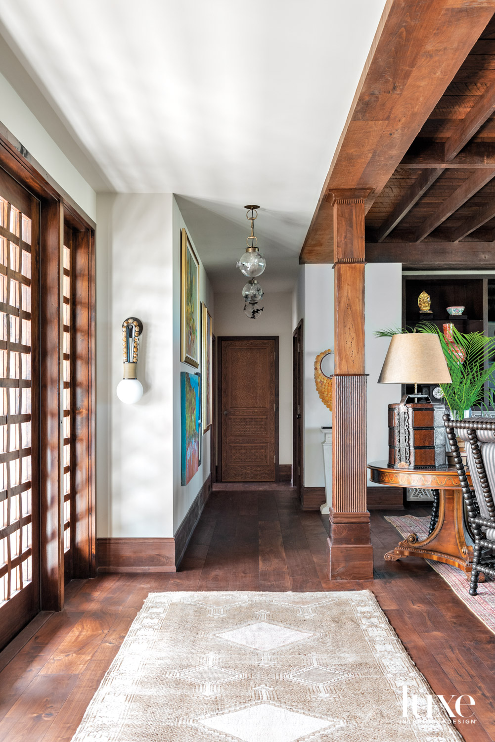 entry with wood architectural details, walnut floors, walnut front door and ceiling lighting pendants in hallway