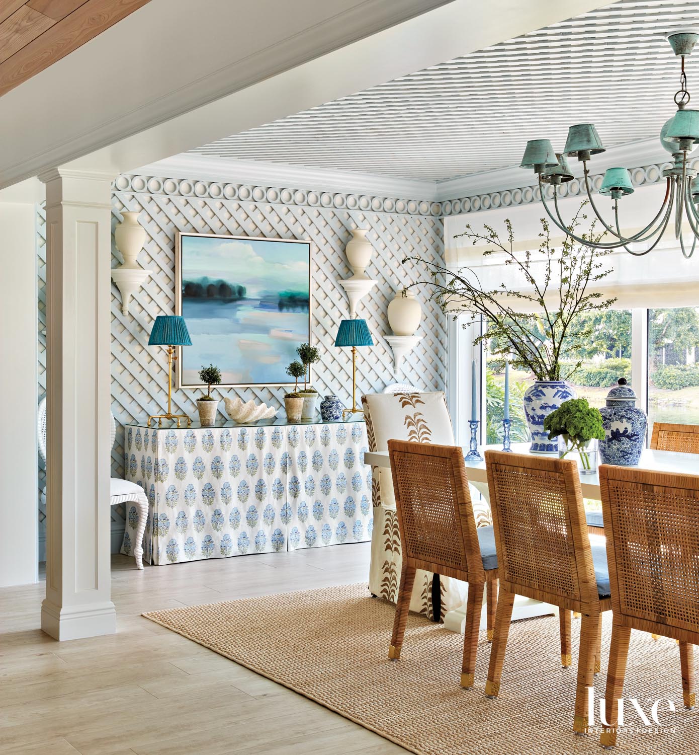 dining room with blue lattice on walls, woven side chairs, fabric head chair, rectangular sofa and french blue chandelier