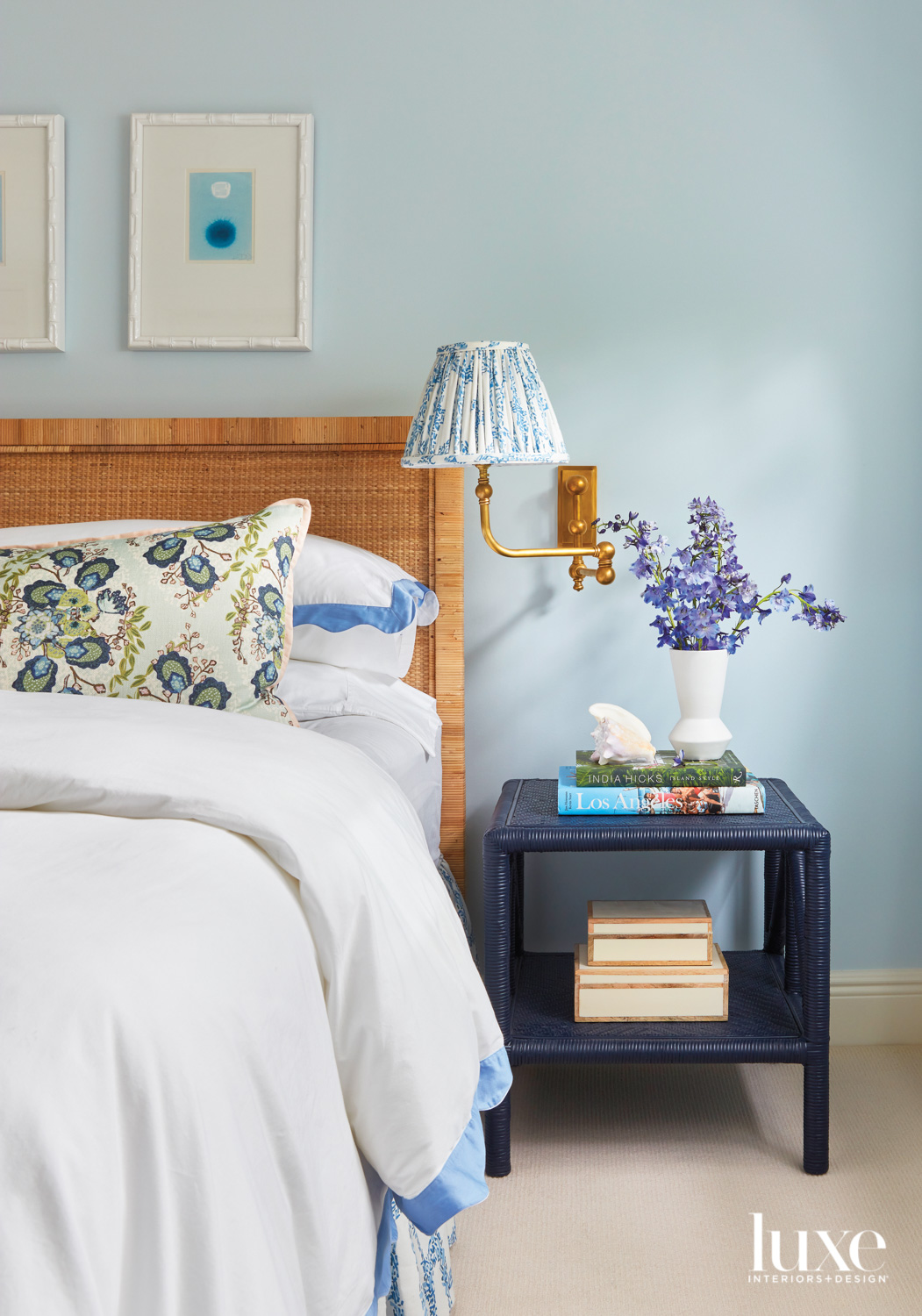 bedroom with rattan bed, navy nightstand, blue walls and white and blue artwork