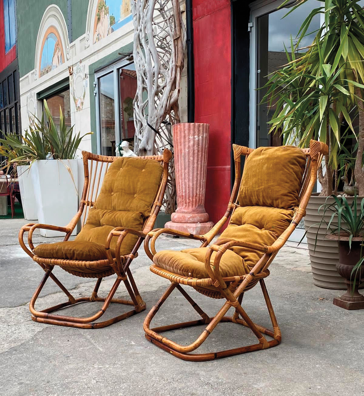 A pair of vintage chairs sitting on a sidewalk in front of a storefront