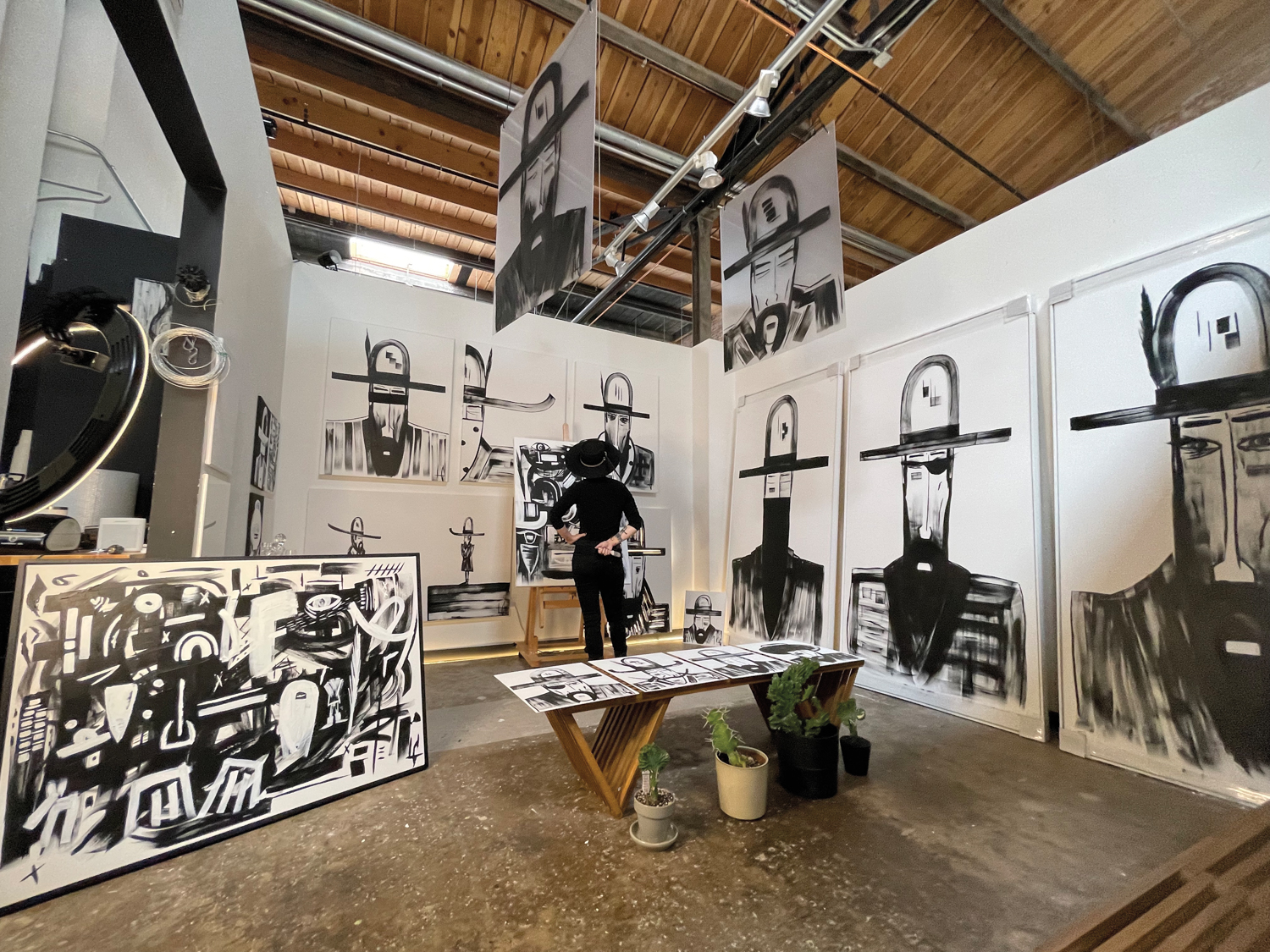 Artist in studio surrounded by paintings of cowboys