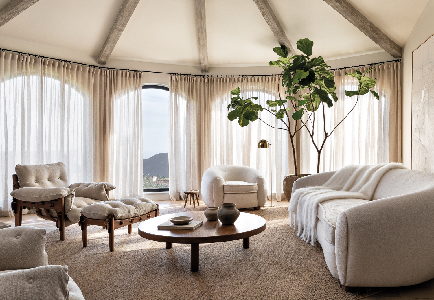 round, curved living room with white furniture and curtains