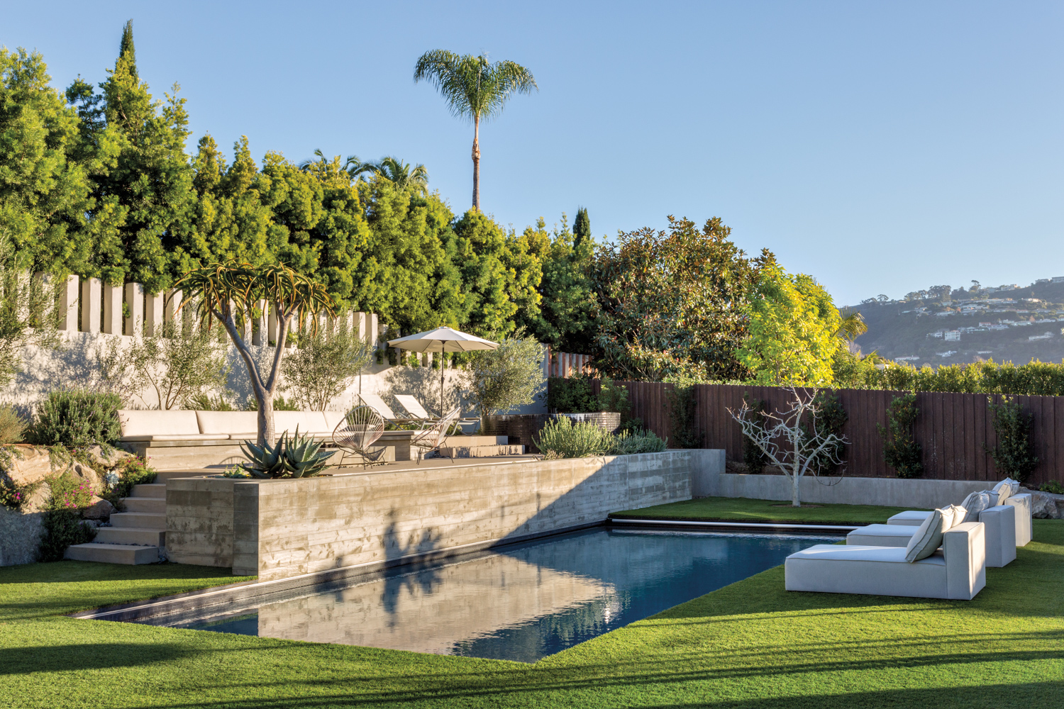 in ground square backyard pool with a raised seating area above