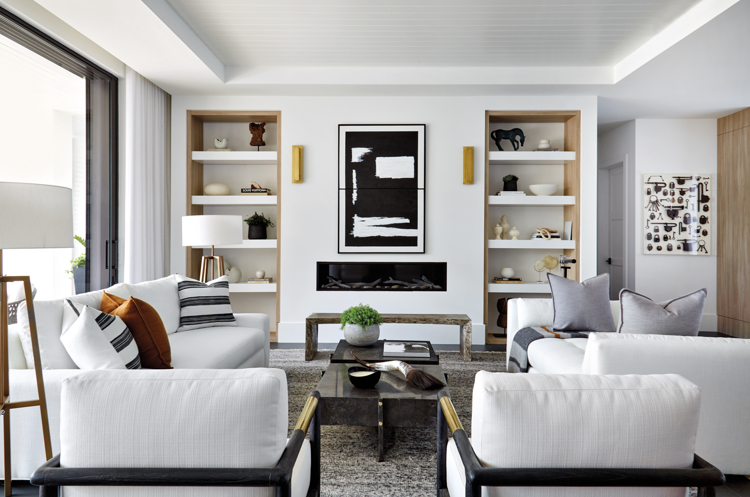 living area with white sofas and walls, black artwork and two built-ins