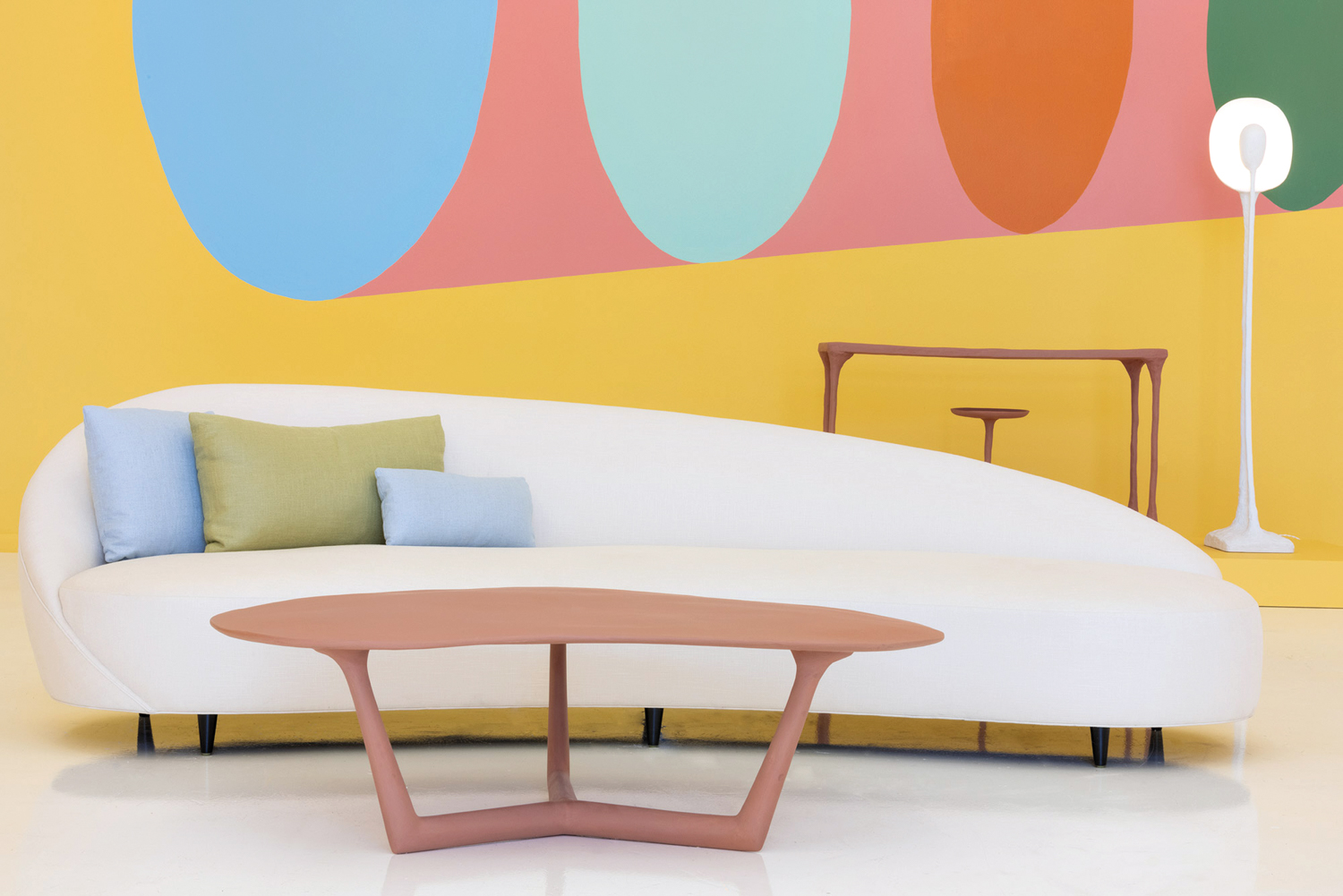 Colorful wallcovering, white curved sofa and sculptural coffee table