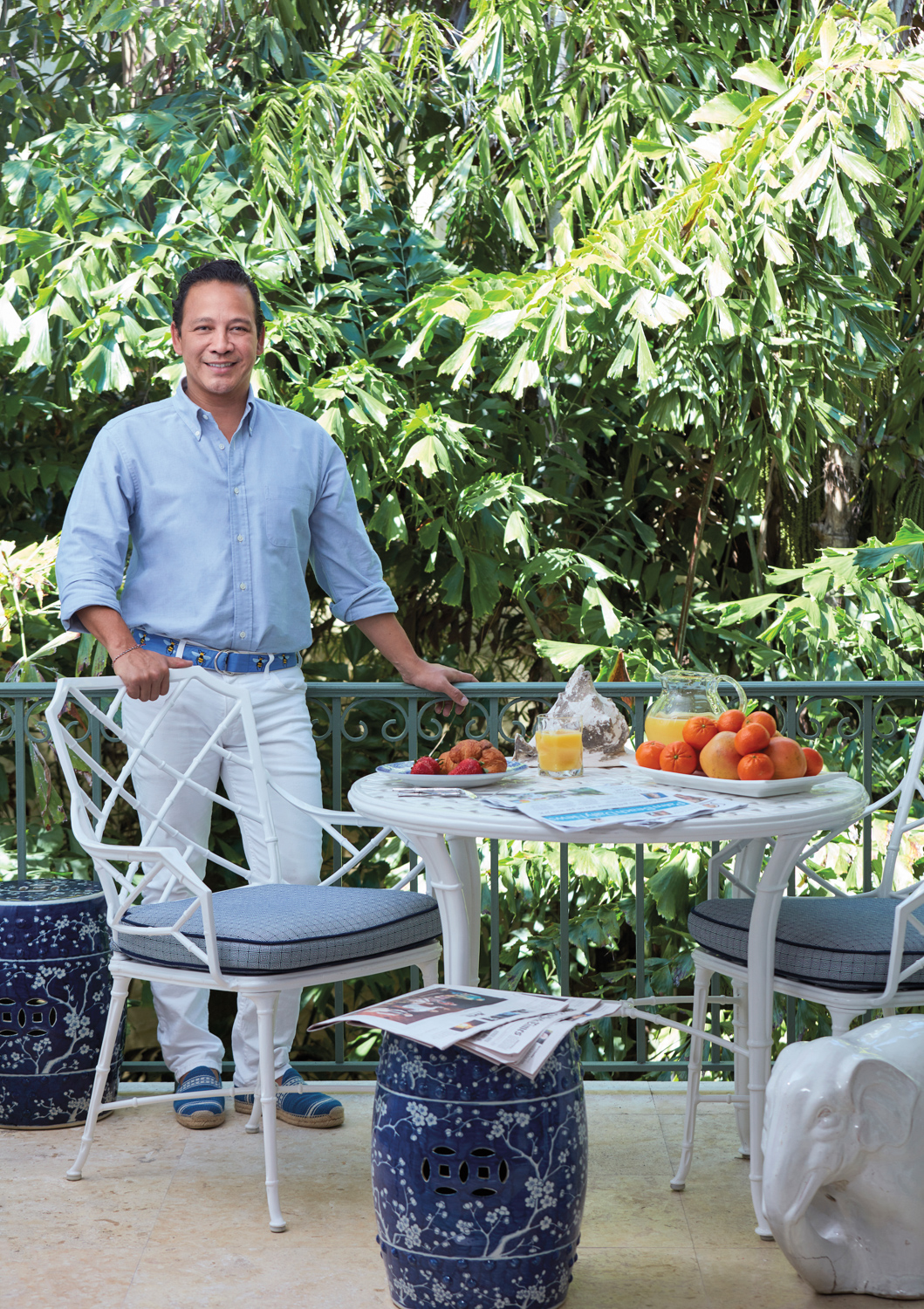 Landscape designer Fernando Wong poses outdoor near a garden table and chairs