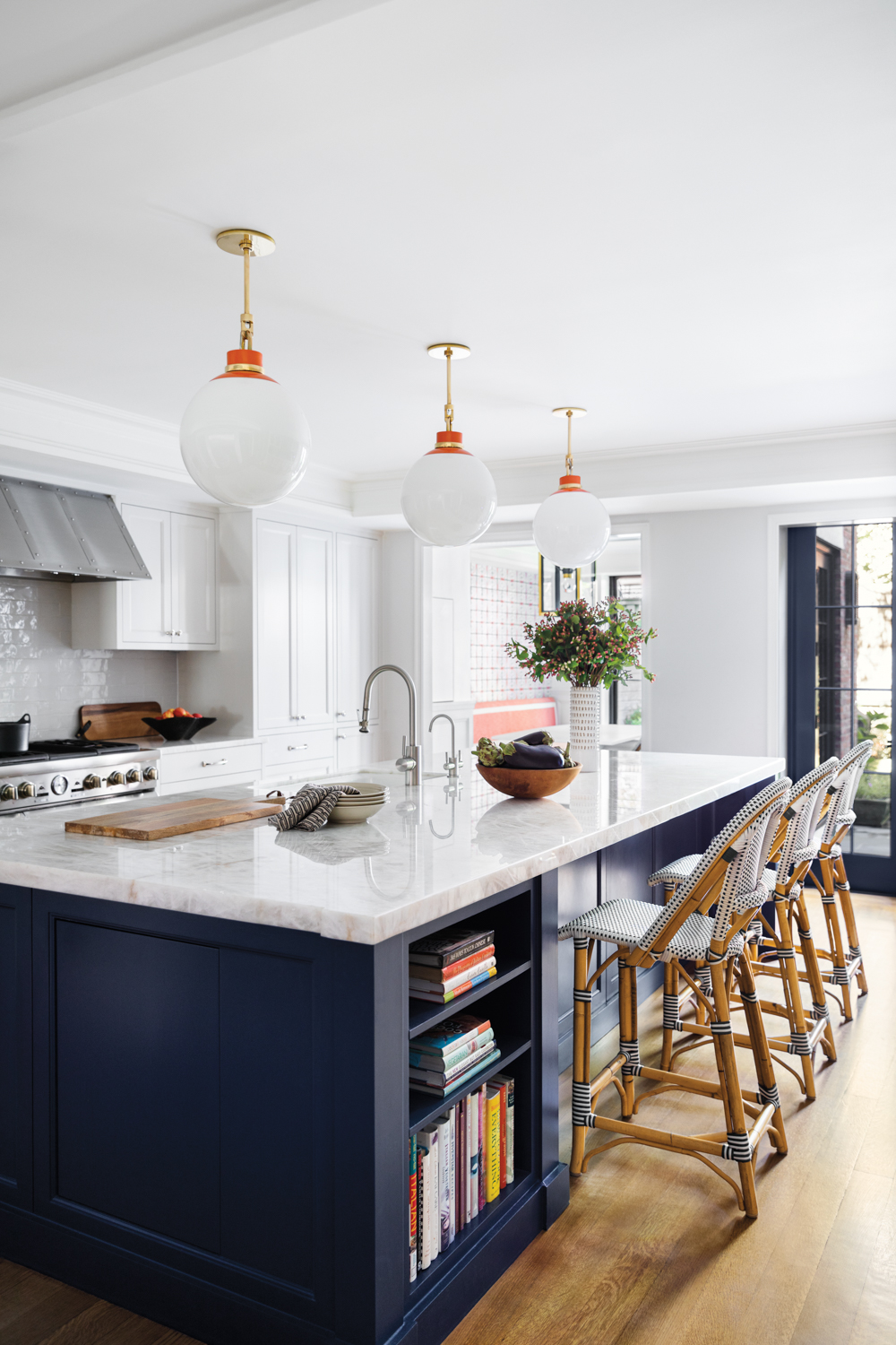 white kitchen with navy island cabinets and globe pendants