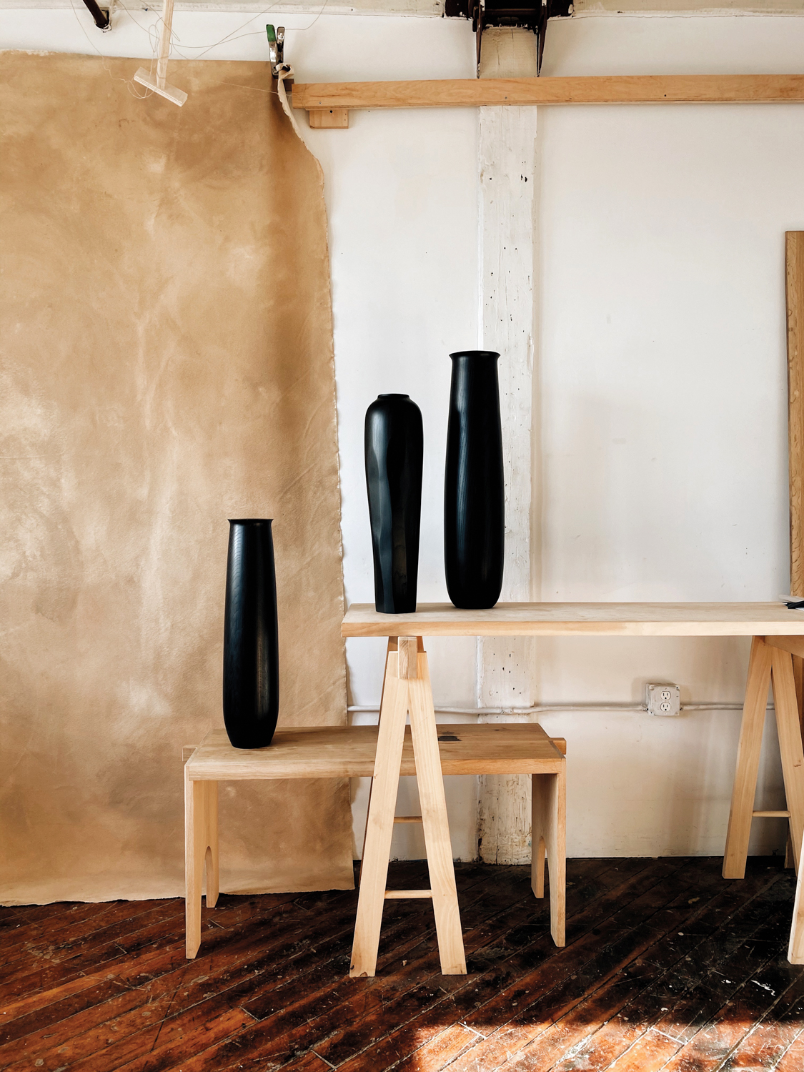 Black tall sculptural vases on wood benches