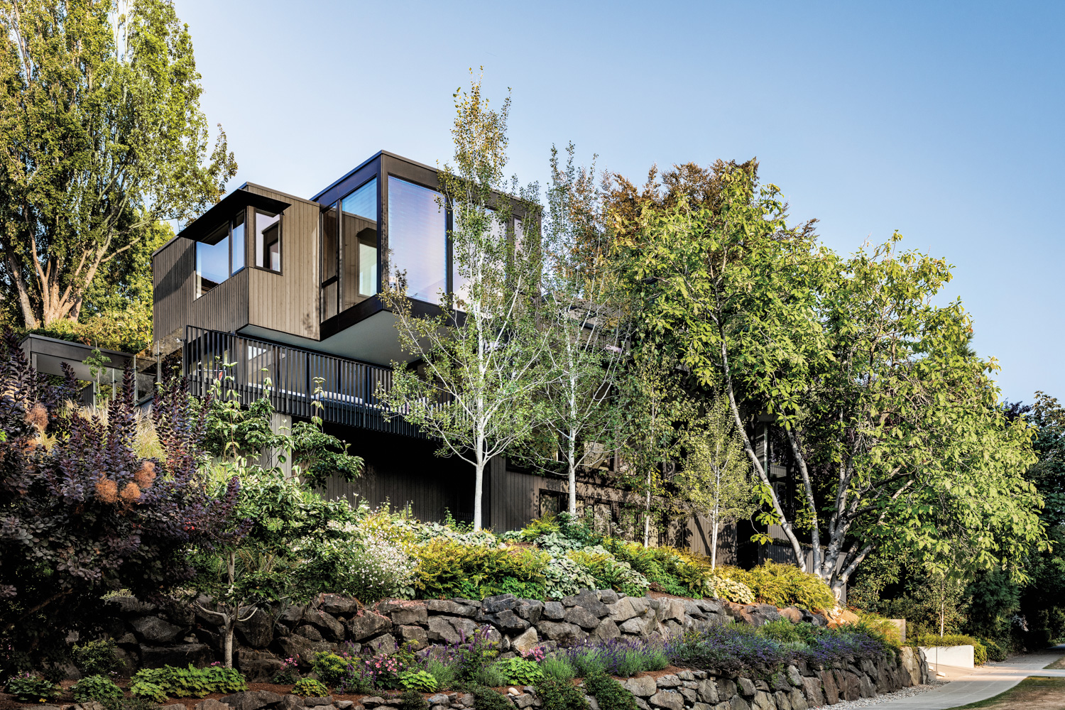 rectilinear exterior of a stacked and stepped modern style hillside home tucked among trees