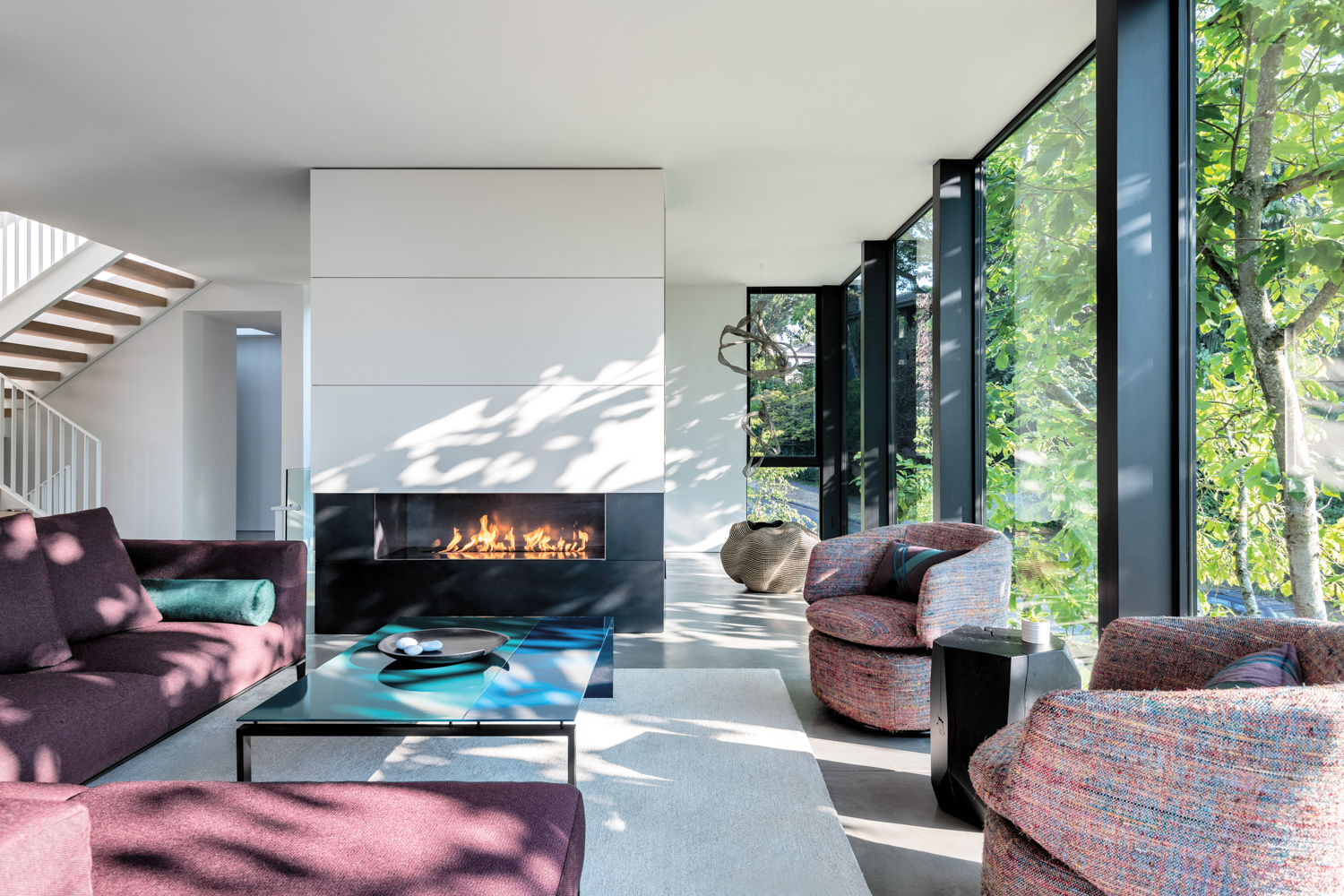 living room with concrete floors and gas fireplace with multicolored swivel chairs and pink colored sectional