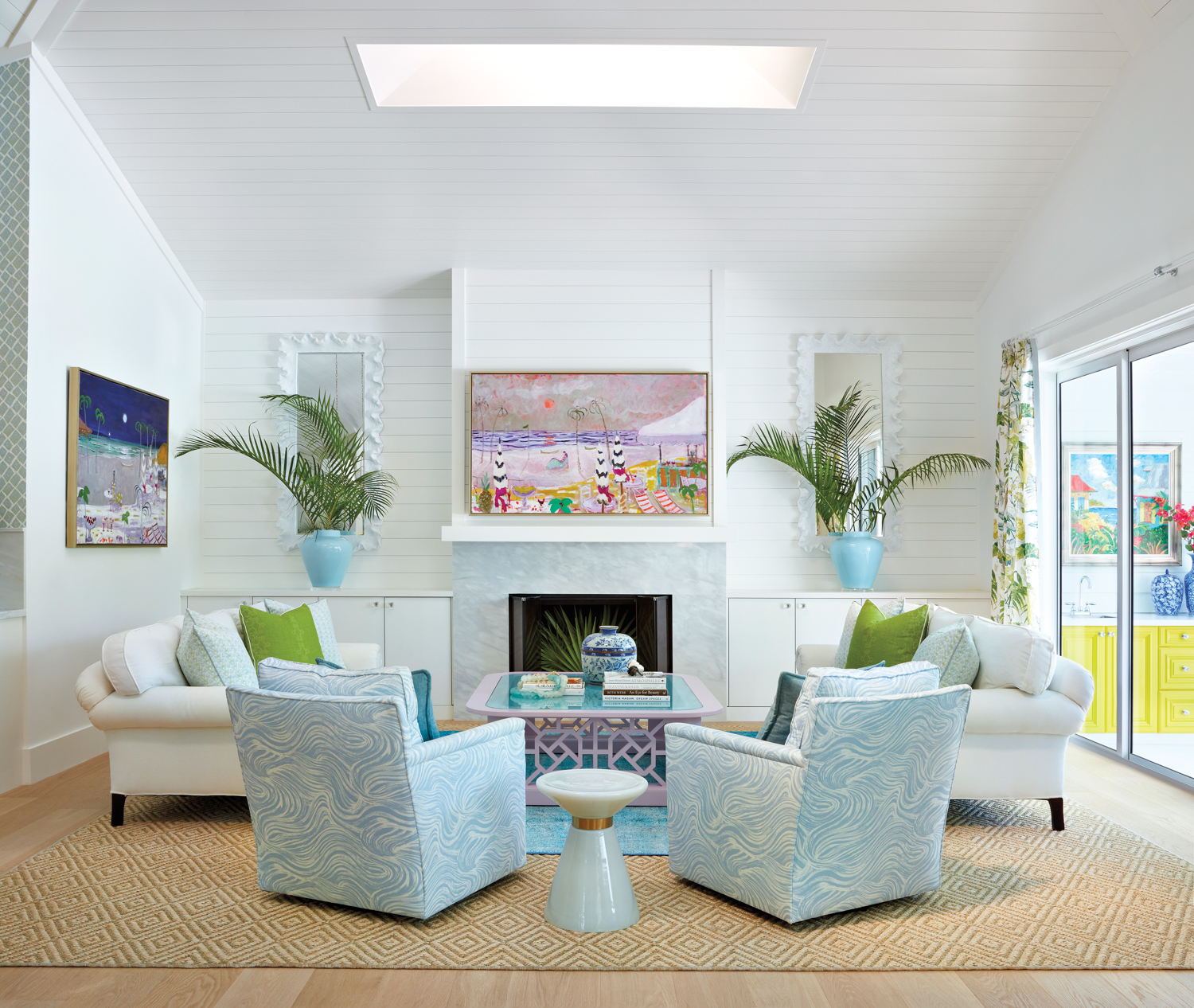 living area with blue print armchairs, colorful art, white walls and fireplace