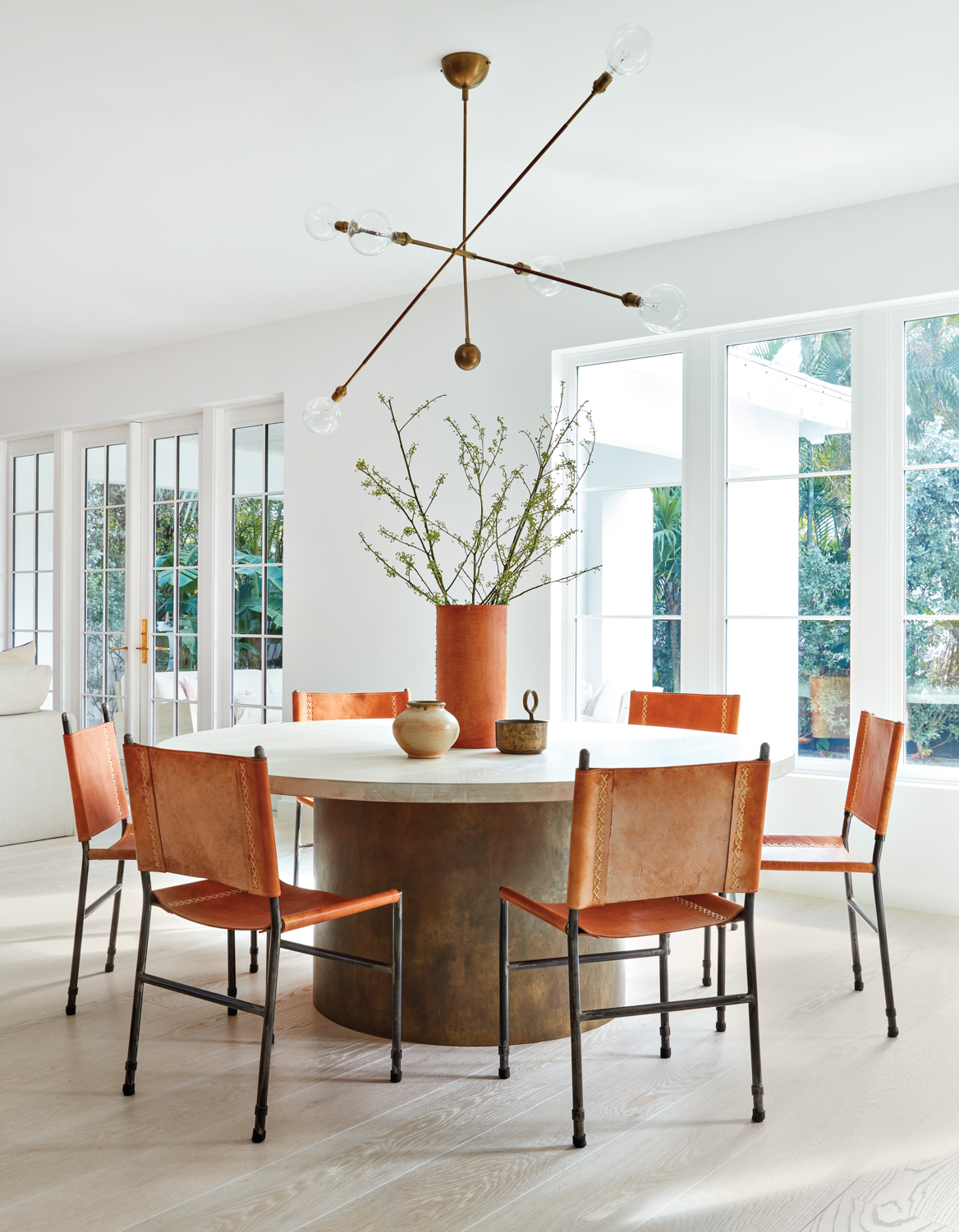 dining area with round table, leather chairs and sculptural chandelier