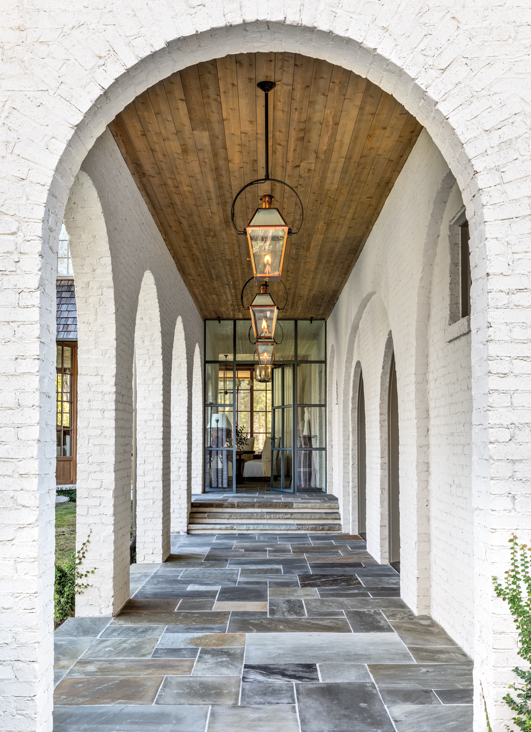 Exterior passageway with brick arches, hanging lanterns and a wooden ceiling