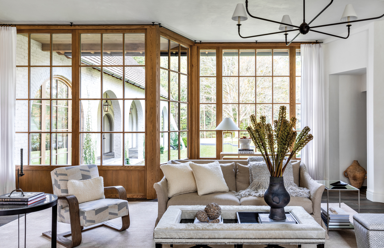 Living room with large wood-framed windows and light-colored upholstery