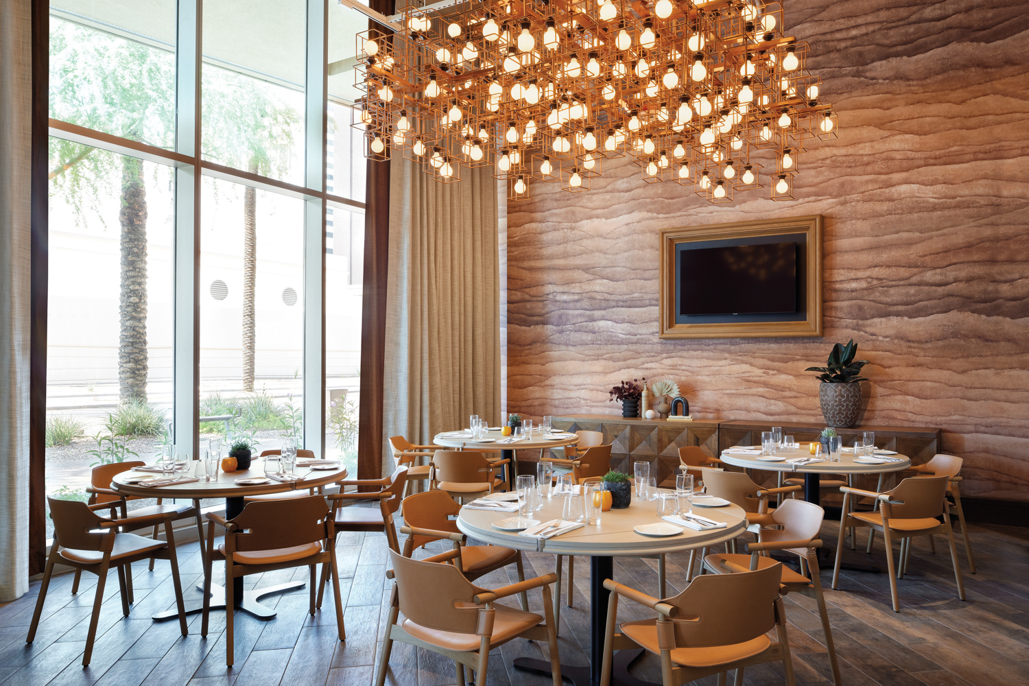 Restaurant with rammed-earth wallcovering and oversize chandelier