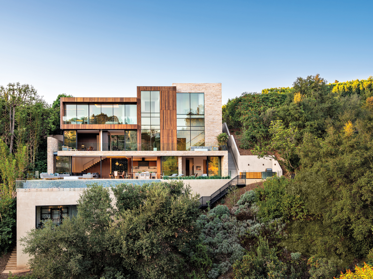 rear façade and expansive pool terrace of a Pacific Palisades home, with outdoor seating and a fire pit