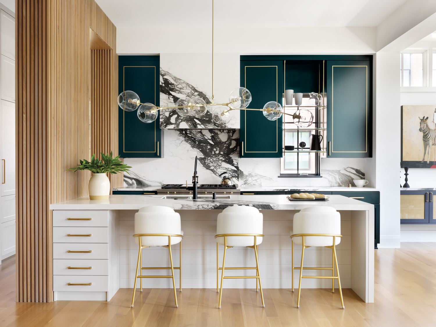 White kitchen island topped with black-and-white porcelain countertop paired with forest-green cabinetry