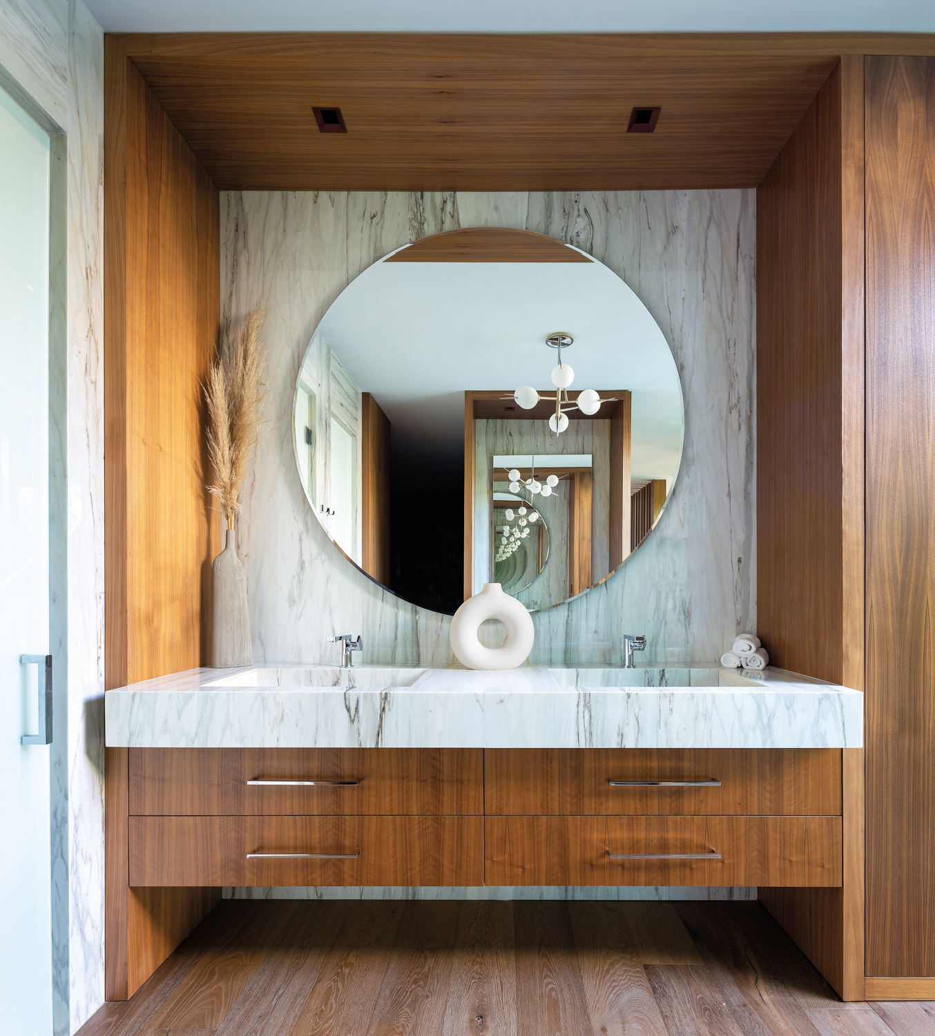 bathroom vanity made of white marble and walnut with round mirror