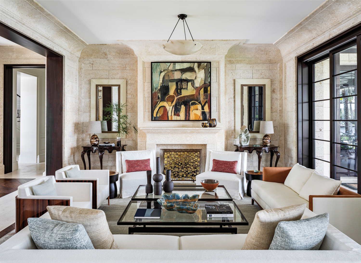 great room with coral stone walls, neutral-toned furnishings and artwork above fireplace