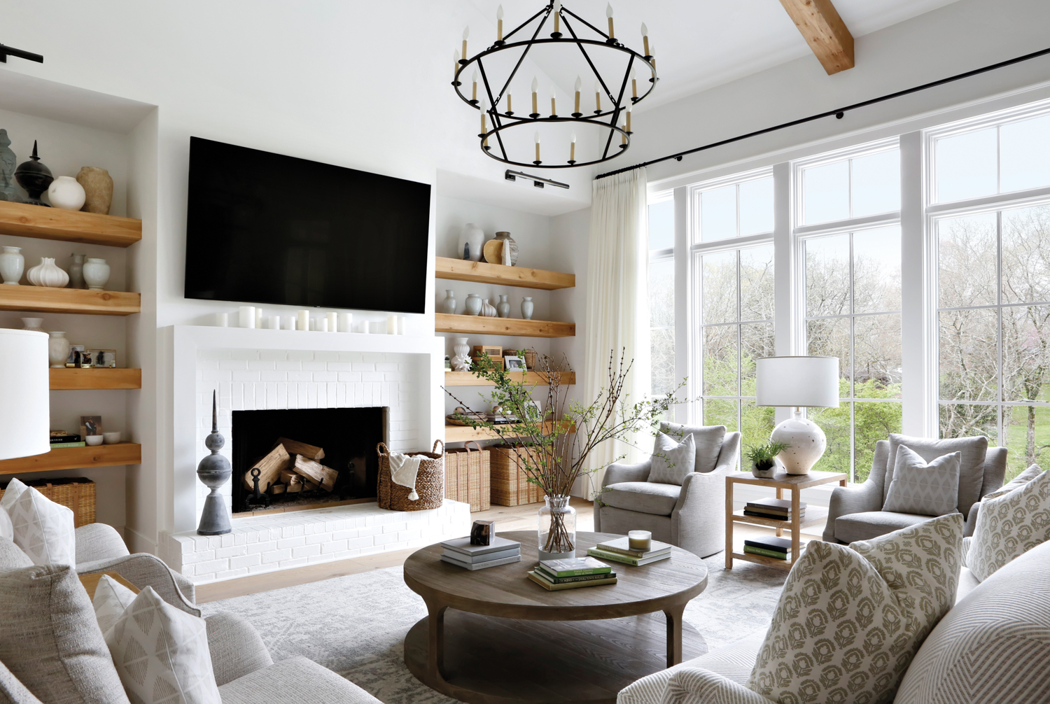 Bright modern farmhouse family room with wooden ceiling beams and a white brick fireplace