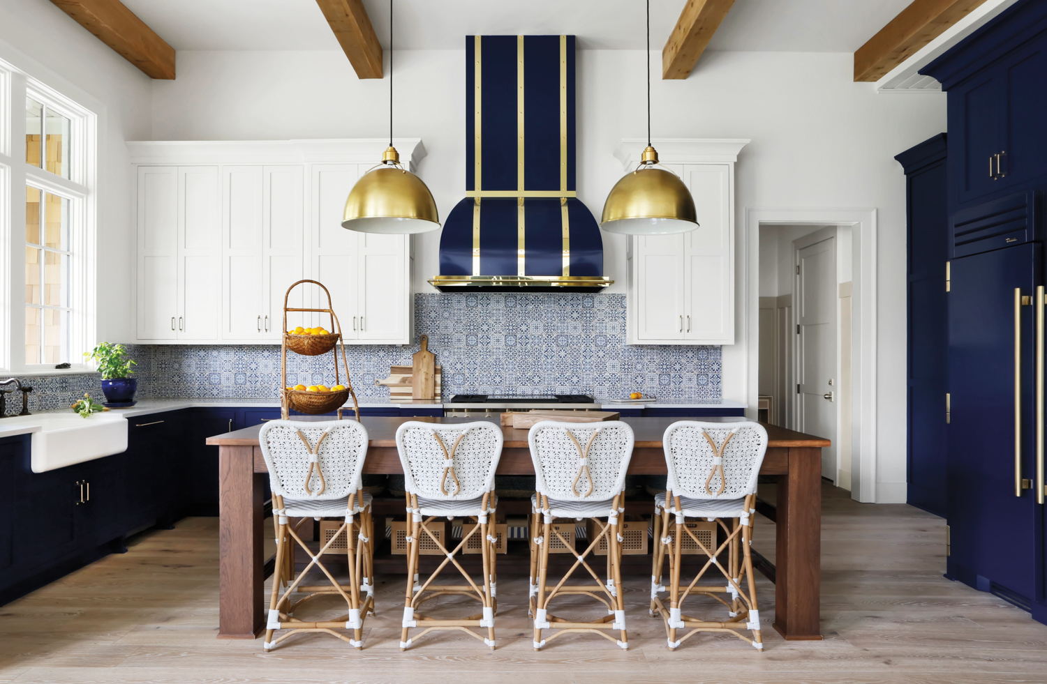 Kitchen with dark blue vent hood, patterned backsplash tile and French-inspired counter stools
