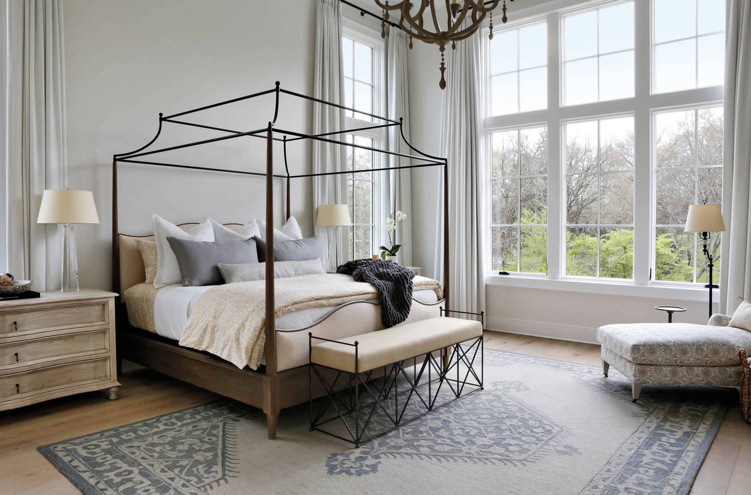 Large, light gray bedroom with canopy bed and tall windows