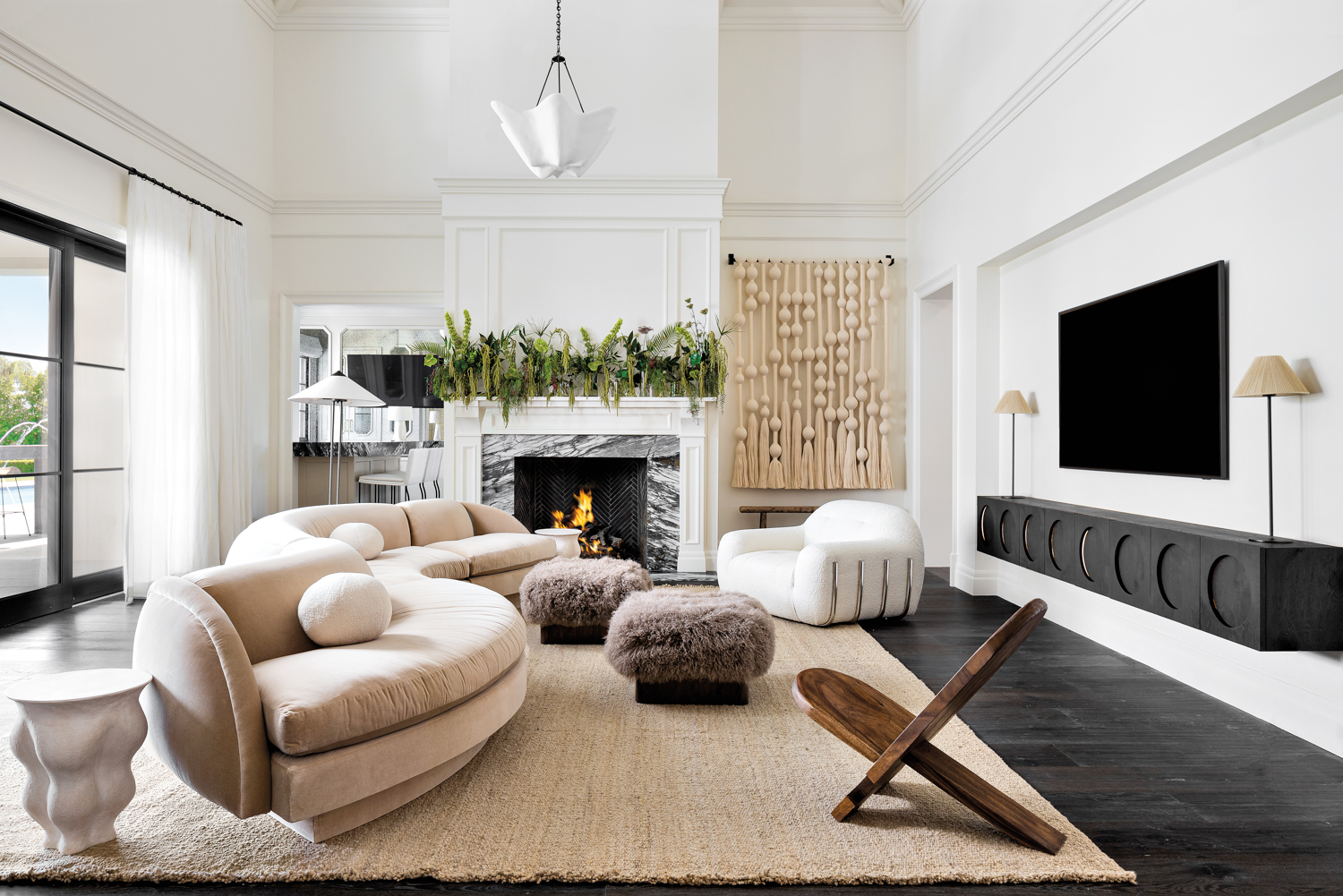 A living room with a serpentine sofa, fur ottomans and a white boucle chair.