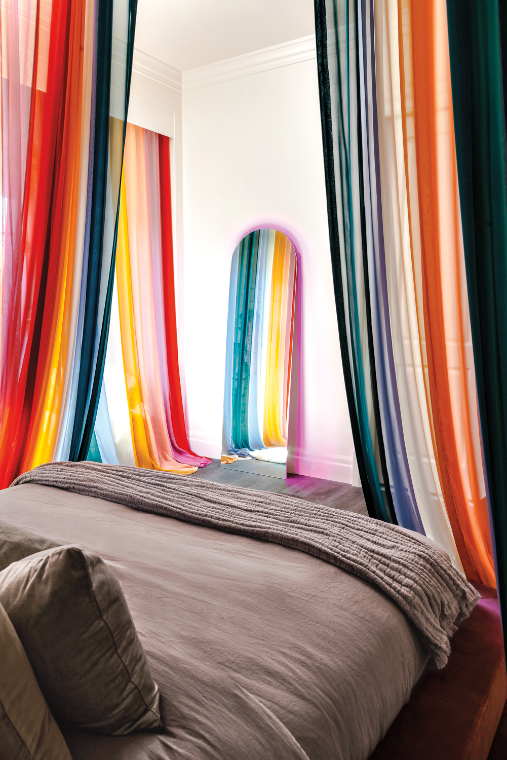 A bedroom with raninbow drapes.