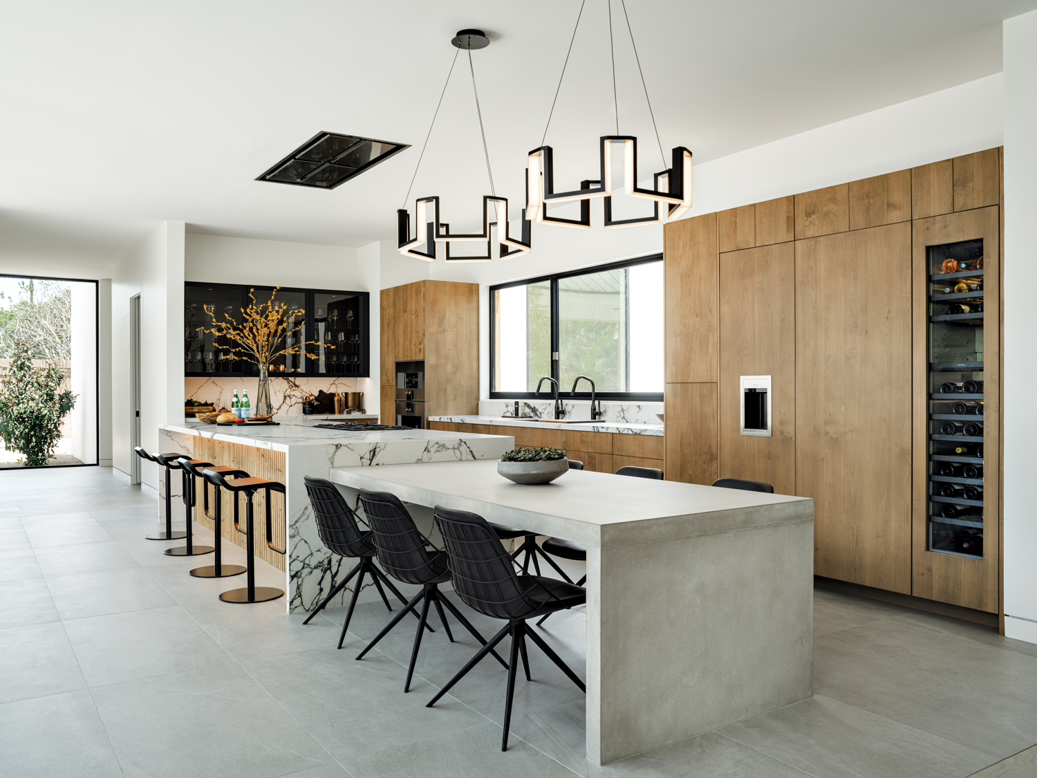 A modern minimalist kitchen with a large island and a large table
