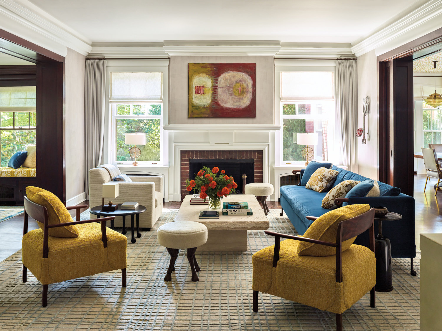 A living room with a brick fireplace, a blue sofa and a pair of yellow chairs.