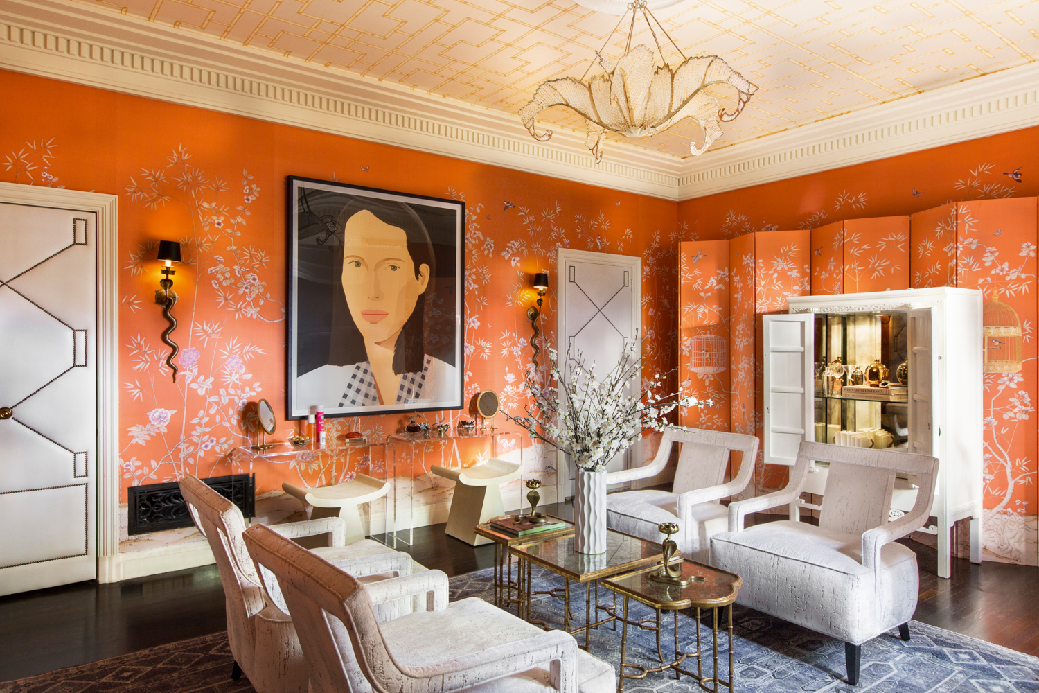 living room with white armchairs, orange wallpaper and artwork of a woman