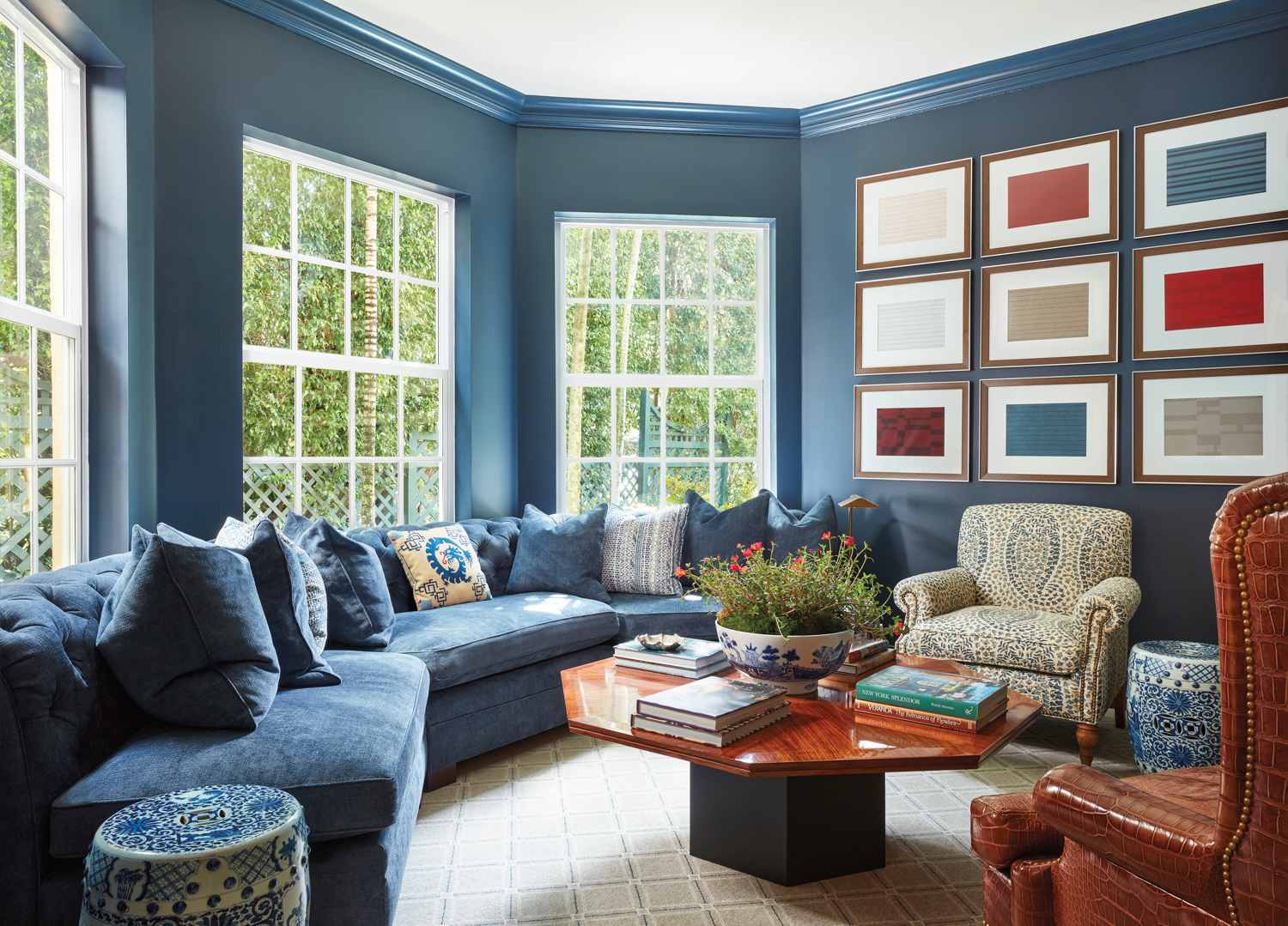 television room with navy walls, curved banquette, and mahogany coffee table
