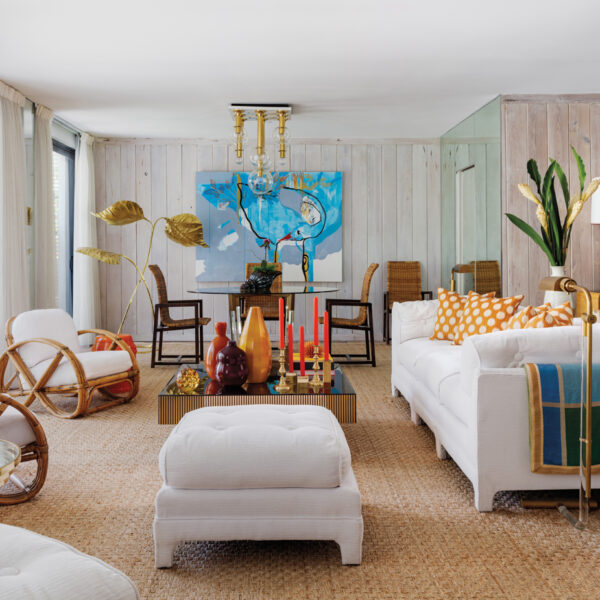 Consider This 1970s Palm Beach Home A Time Capsule Reopened living area with rattan pretzel chairs, upholstered white furnishings, large sisal rug, dining area and blue artwork