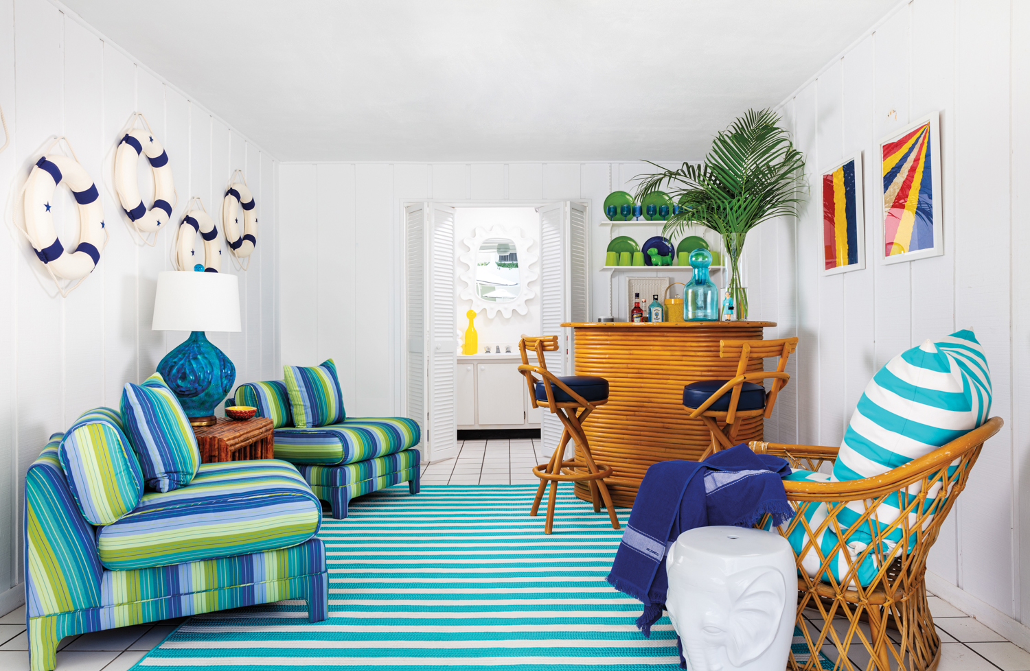 cabana with wicker bar and stools, blue striped rug and striped armchairs