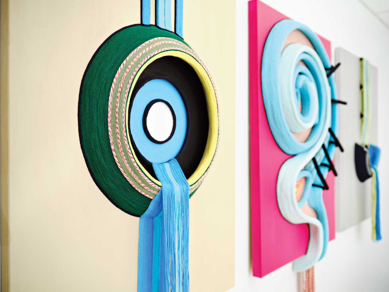 colorful three-dimensional yarn artwork by michelle drummond hanging on a wall