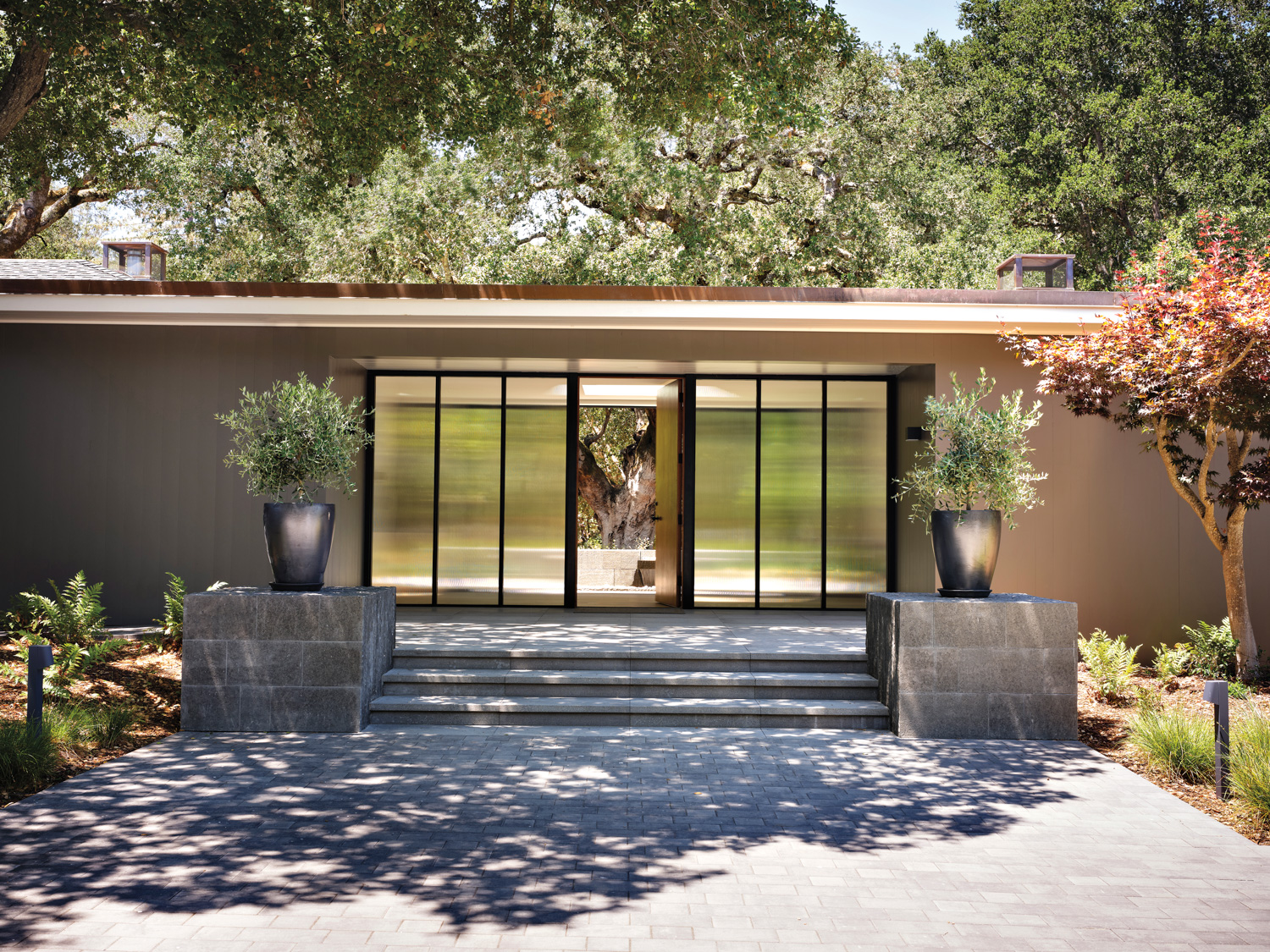 The exterior of a modern home has large glass doors.