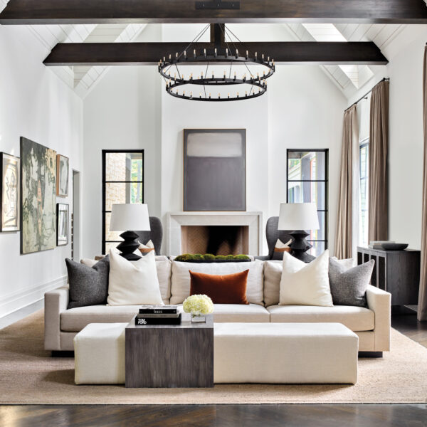 Tour A Texture-Rich Atlanta Home That’s Both Hip And Handsome Vaulted family room with streamlined furniture, wooden ceiling beams and tiered chandelier