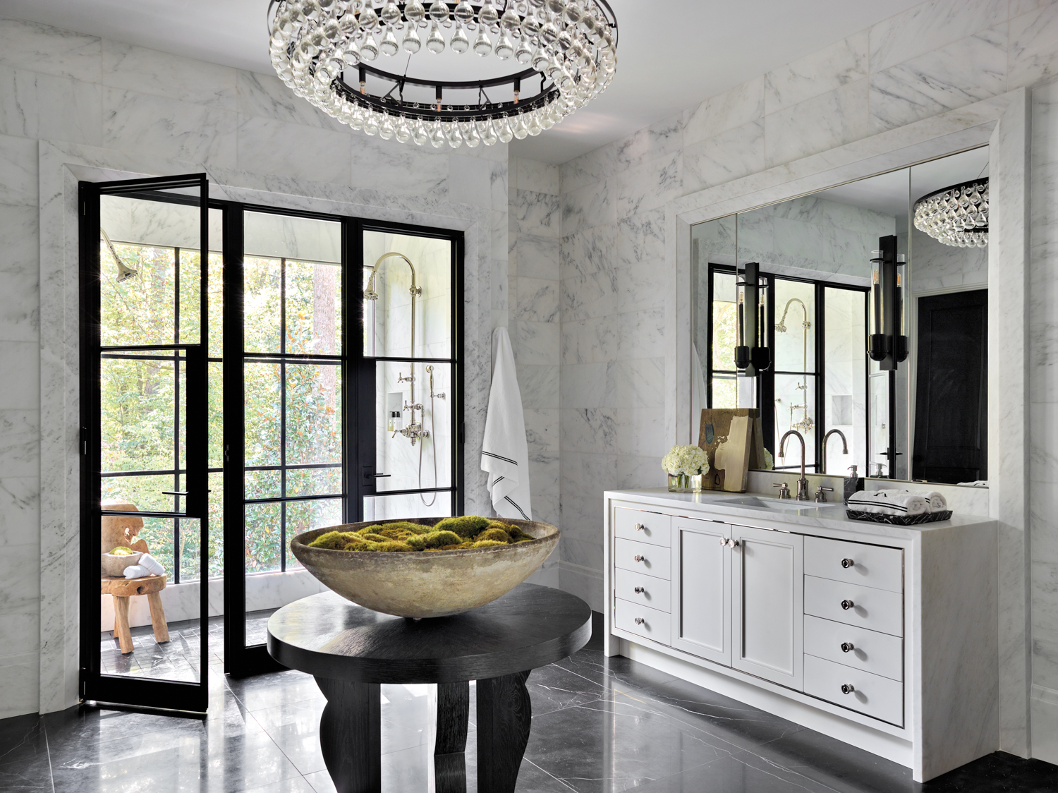 Large bathroom with marble walls, round table and contemporary crystal chandelier