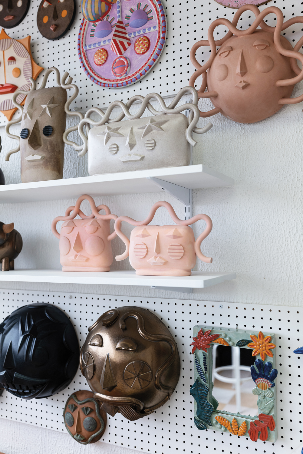 Shelves lined with whimsical face vessels in various colors
